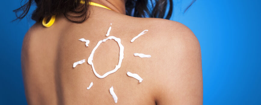 Loção bronzeadora no braço da mulher em forma de sol