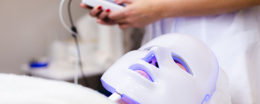 O cliente está deitado na sala na mesa de cosmetologia com uma máscara branca no rosto