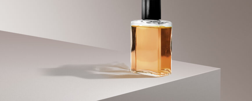 Frasco de perfume sobre fundo de produto rosa