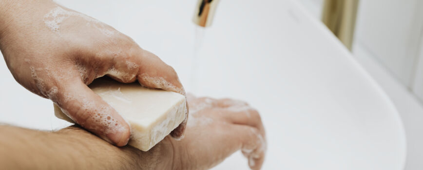 Homem usando uma barra de sabão para lavar as mãos