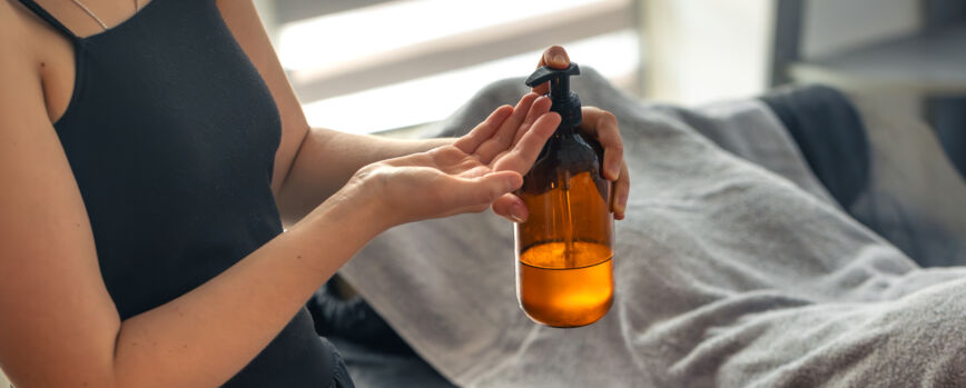 Mulher com garrafa de óleo cosmético, produto moderno para o cuidado da beleza