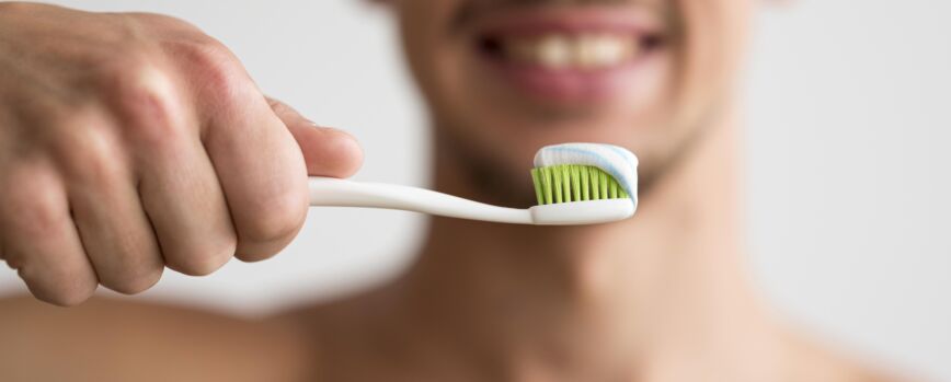 Vista frontal do homem desfocado com escova de dentes com pasta de dentes nela