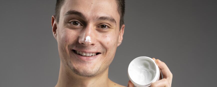 Homem bonito jovem com um creme para acne