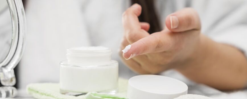 Mão em primeiro plano com creme no dedo