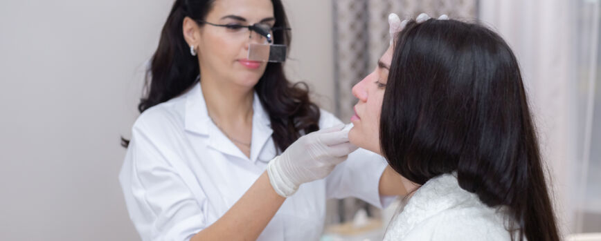 Um cliente em uma consulta com um esteticista, consulta, modelagem do rosto, preparação para os próximos procedimentos, exame visual das áreas problemáticas.