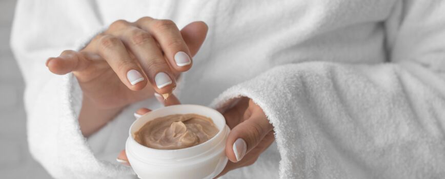 Mãos em close segurando o recipiente de creme