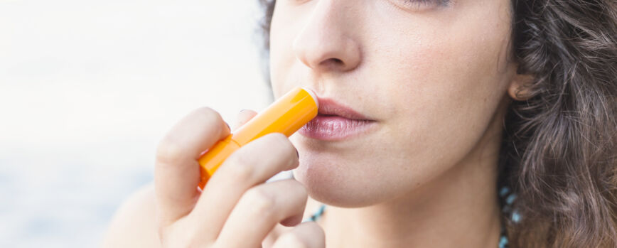 Close de mulher jovem aplicando bálsamo labial