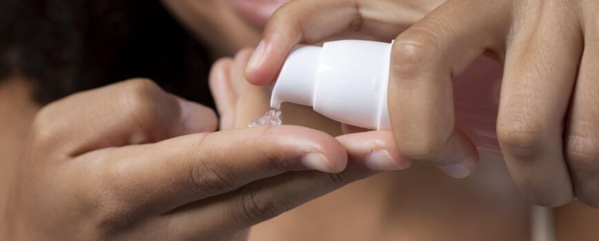 Bela modelo aplicando um tratamento de creme cosmético em seu rosto em branco