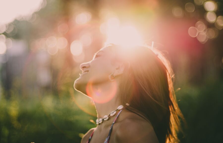 Uma mulher tomando sol com um sorriso vibrante e um estado de espírito despreocupado ao ar livre.