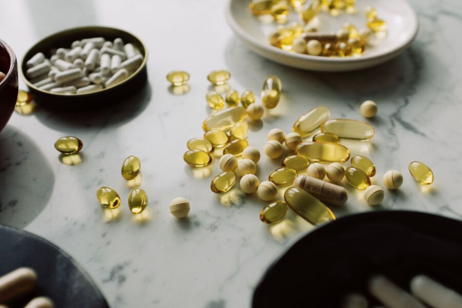 Um primeiro plano de pílulas e suplementos variados dispostos sobre uma superfície de mármore, destacando temas de saúde e bem-estar.