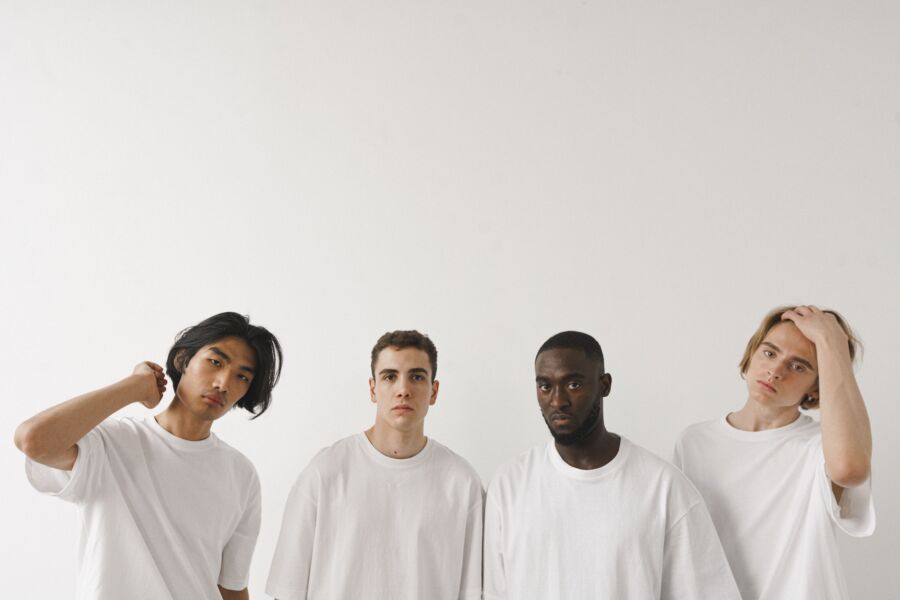 Quatro jovens diversos posando em um estúdio minimalista com fundo branco.