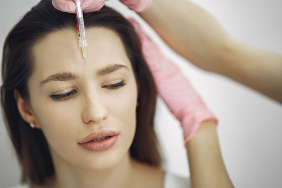 Close-up do tratamento facial com injeção em um ambiente de spa, focando na testa.