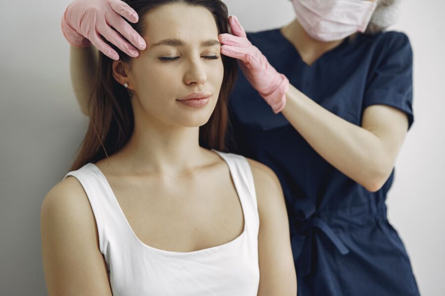 Mulher recebendo uma massagem calmante na cabeça de um terapeuta em um ambiente de spa.